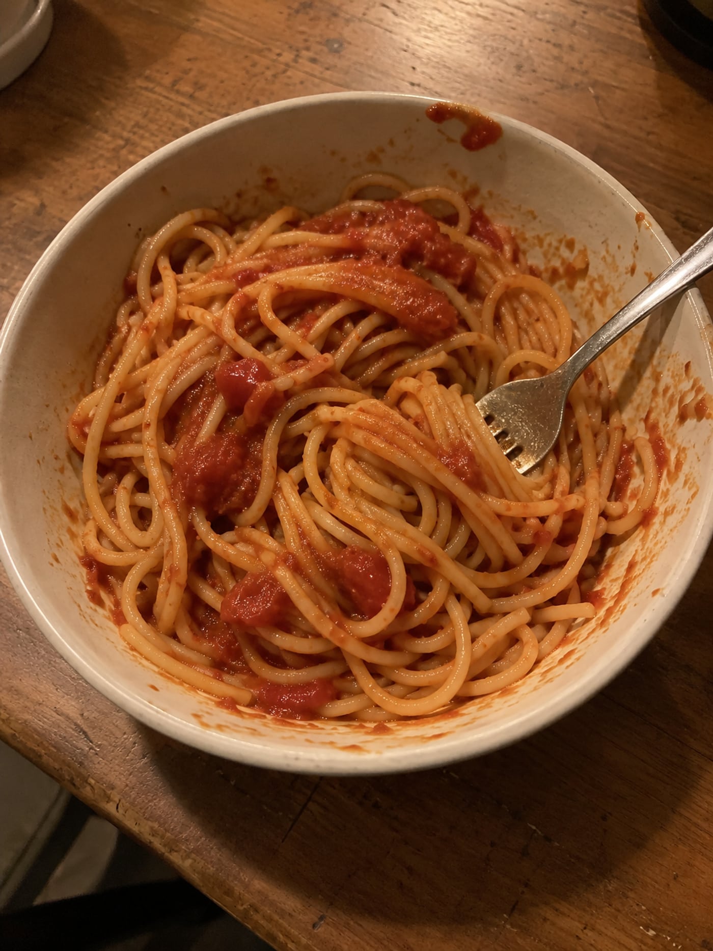 An ordinary bowl of tomato pasta on a wooden kitchen table